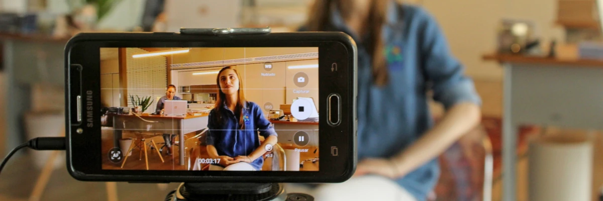 Lo schermo di un cellulare mentre riprende una ragazza in uno studio professionale. I tuoi video per il web sono uno strumento formidabile di promozione